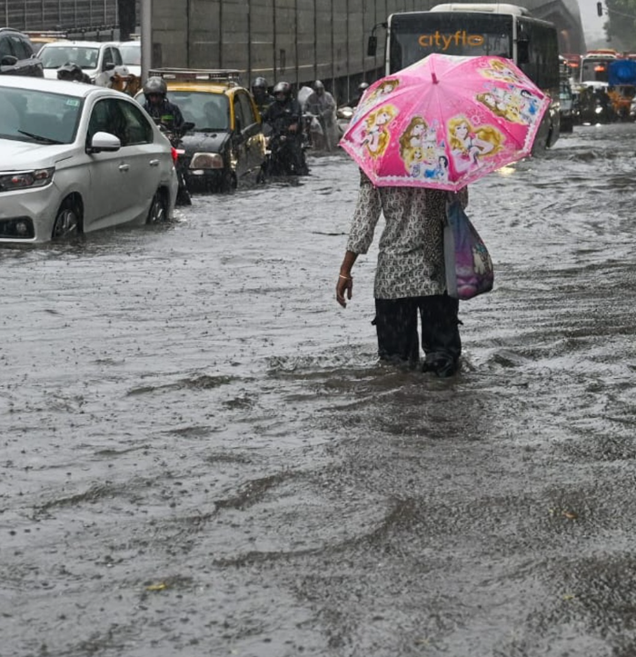 A woman walking on a road flooded with water